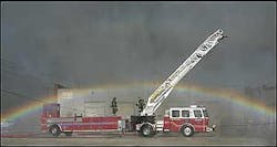A rainbow forms in the spray from a nearby aerial snorkle truck Wednesday, July 20, 2005, over a Kansas City Fire Department truck at the scene of a four-alarm fire at ABC Tire in the West Bottoms of Kansas City, Mo.