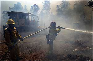 City of Redding firefighter Mike Lowrey, left, and Capt. Ed Andrews cool off the left flank of a fire the burned about 34 acres on Monday, July 25, 2005, in Redding, Calif. Dozens of houses where threatend in the area of Gold Hills Golf Club. No structures were burned and the fire was contained by midafternoon.