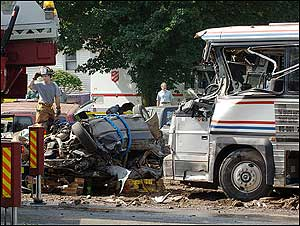 An Avon fire department captain, left, stands near the remains of a fiery multiple vehicle crash that killed several people, Friday, July 29, 2005, in Avon, Conn.