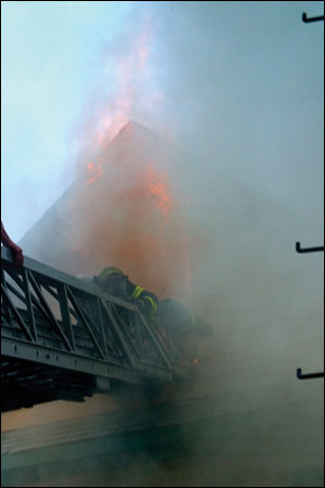 After the firefighter entered the attic and checked for fire extension, the attic flashed over. The firefighter made it onto the aerial ladder despite fire venting from the top of the attic window.