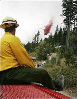 Firefighter Steve Cope sits on top a fire truck and watches a plane drop fire retardant near houses at the base of Dirtyface Mountain near Lake Wenatchee, Wash., Monday, Aug. 1, 2005, ahead of a wildfire that is threatens homes in the Whispering Pines subdivision. The wildfire believed to have started in a burning mobile home before igniting nearby brush had grown to more than 960 acres by Monday evening and threatened more than 140 homes, fire officials said. Firefighter Steve Cope sits on top a fire truck and watches a plane drop fire retardant near houses at the base of Dirtyface Mountain near Lake Wenatchee, Wash., Monday, Aug. 1, 2005, ahead of a wildfire that is threatens homes in the Whispering Pines subdivision. The wildfire believed to have started in a burning mobile home before igniting nearby brush had grown to more than 960 acres by Monday evening and threatened more than 140 homes, fire officials said.