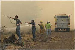 Residents armed with garden hoses assist a firefighter along a dirt maintenance road as fire threatens the Waikoloa Village housing subdivision on the Big Island of Hawaii, Tuesday, Aug 2, 2005. The dirt road served as a fire break and kept the fire from burning several nearby houses. Residents armed with garden hoses assist a firefighter along a dirt maintenance road as fire threatens the Waikoloa Village housing subdivision on the Big Island of Hawaii, Tuesday, Aug 2, 2005. The dirt road served as a fire break and kept the fire from burning several nearby houses.