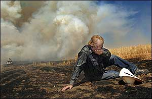 Dion Hagen covers his face as he is overcome by smoke and heat while fighting wheat field fire east of Dutton, Mont., Thursday, Aug. 4, 2005. Hagan is among the many neighbors and nearby landowners who responded with their farming equipment to help battle the blaze.