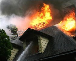 A firefighter retreats from the heat and flames of an early morning fire in a three-story house in Jersey City, N.J., Monday, Aug. 8, 2005. The three occupants escaped without injury.