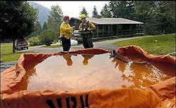 Tom McIsaac, left, and Brant Waldron, both with the Frenchtown Fire department, talk structure protection, behind a portable water supply, at a home on West Mountain Road near Alberton, Mont., as a wildfire burns nearby Monday, Aug. 8, 2005. Tom McIsaac, left, and Brant Waldron, both with the Frenchtown Fire department, talk structure protection, behind a portable water supply, at a home on West Mountain Road near Alberton, Mont., as a wildfire burns nearby Monday, Aug. 8, 2005.