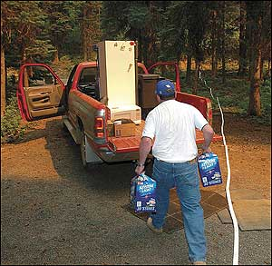 Ed Crawford of Pomeroy, Wash., loads up his vehicle at his Stentz Springs cabin, near Pomeroy, Wash., Tuesday, Aug. 9, 2005. Fire managers now have more than 1,300 firefighters on the aggressive School fire in southeast Washington. More than 130 engines and pumpers are on that blaze, which started Friday and blew up over the weekend.