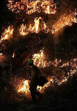 A firefighter working near the South Fork of the Clearwater River uses a drip torch to set a night-time backfire late Saturday, Aug. 13, 2005 at the Blackerby Fire near Grangeville, Idaho.
