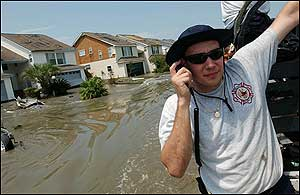 Firefighter Eric Abney rides on the side of a rescue vehicle after collecting evacuees from the Eden Isles subdivision in Slidell, La.