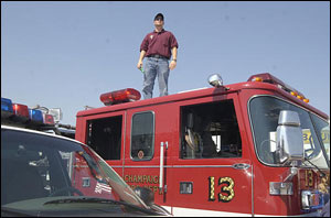 Peter Farm, a firefighter with the Cornbelt Fire Department, stands on top of a fire truck and looks the over fire trucks and firefighters from various Illinois fire departments at a staging area in a truck stop in Effingham, Ill., Monday, Sept. 5, 2005. They are heading south in teams for duty in Hurricane Katrina ravaged areas.