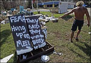 Carpenter Alan Perkins walks past a sign put up by another resident living in a tented city in Bay St. Louis, Miss., Thursday, Sept. 8 , 2005. The victim of Hurricane Katrina put up the sign after she called four times for FEMA's assistance and was always prompted to leave a message. The sign reads, 'FEMA hung up on me. They said they were too busy to help'.
