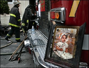 A photo of a baby sits on the bumper of a fire truck after it was recovered by a firefighter from one of the burned out units in a two-story apartment building where three people died and nearly a dozen others were injured.