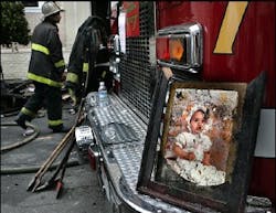 A photo of a baby sits on the bumper of a fire truck after it was recovered by a firefighter from one of the burned out units in a two-story apartment building where three people died and nearly a dozen others were injured.
