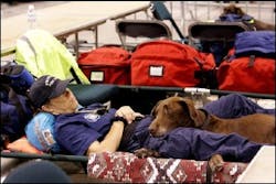 Kim Norman,of the Phoenix Fire Department, rests on a cot with rescue dog Reo as they wait in Houston for winds from Hurricane Rita to subside enough to fly over storm wrecked areas and assess the damage Saturday, Sept. 24, 2005.
