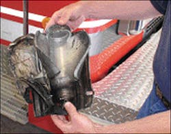 Author holds the two components of the frontal airbag unit that exploded in the McKinney, TX, incident. Note that the stored-gas inflator cylinder has ruptured in a fashion similar to a BLEVE. The inflator and the backing plate landed just over 120 feet away from the burning vehicle after the explosion.