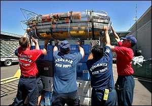 From left; Phoenix firefighter recruit Rory Costello, Capt. Tom Henry, Capt. Gilbert Cardenas and recruit Todd Yonker hoist rescue baskets atop a pallet of rescue supplies in this Tuesday, Aug. 30, 2005, file photo at the Phoenix Firefighter Training Academy in Phoenix, prior to leaving for New Orleans. Phoenix Fire department, which sent their search and rescue team to assist in the aftermath of Hurricanes Katrina and Rita, has had it's search and rescue teams suspended from operations by FEMA becasue it sent armed police officers to protect the firefighters during their deployement to the Gulf Coast. At issue is a rule in FEMA's Code of Conduct that prohibits Urban Search and Rescue teams from having firearms.