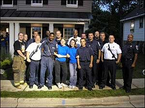 Extreme Makover Firefighters and Paramedics pose with two of the shows producers in front of the new home.