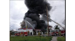 Aerial master streams are played on the burning automotive repair shop. Seven cars and hundreds of tires were lost in the fire, which took two hours to bring under control.