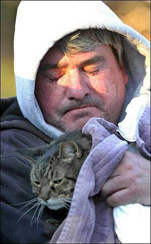Hugh Griffith, a resident in one of the damaged condos, hugs his cat, Calvin, who was rescued by firefighters.