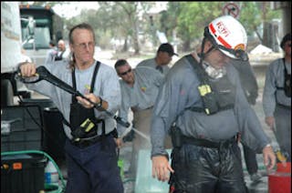 FL-TF1 Hazmat Specialist Hal Martin, left, uses a pressure water cleaner to decontaminate FL-TF1 member John Smithies after a day of searching homes in the Ninth Ward. Pressure cleaners were necessary to remove the thick mud that covered task force members from head to toe.