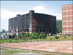 The northeast corner of the warehouse after the fire was extinguished. The brick walls were knocked out of the first two floors of the building to allow water application to the burning materials. The third through the sixth floors were empty. Shredded plastic material was stored in four-by-four-by-four-foot boxes stacked three high on pallets. The warehouse to the right was of identical construction and used for storage of shredded plastic. This warehouse was full on all six floors. The northeast corner of the warehouse after the fire was extinguished. The brick walls were knocked out of the first two floors of the building to allow water application to the burning materials. The third through the sixth floors were empty. Shredded plastic material was stored in four-by-four-by-four-foot boxes stacked three high on pallets. The warehouse to the right was of identical construction and used for storage of shredded plastic. This warehouse was full on all six floors.