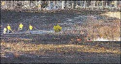 Seacoast firefighters pull hoses across a burned field in Newmarket as they pursue a brush fire on Monday. Seacoast firefighters pull hoses across a burned field in Newmarket as they pursue a brush fire on Monday.