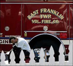 A man sits next to an East Franklin Township Volunteer Fire Co. truck at the firehouse in Franklin Township, N.J., after Apuzzio died in a house fire the morning of April 11.