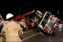 A Prince George's firefighter observes a tower ladder that rolled on its side while responding to a structure fire. A Prince George's firefighter observes a tower ladder that rolled on its side while responding to a structure fire.