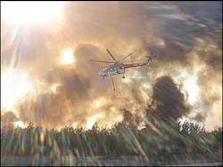 A helicopter releases water on a fire in San Marcial, N.M.