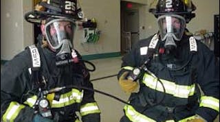 Two firefighters connected to an Emergency Breathing Support Systems (EBSS). Once connect, the mobility of both firefighters will be restricted.