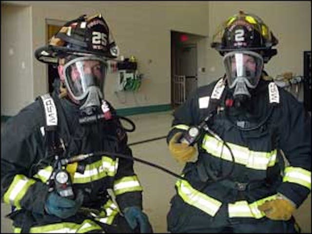 Two firefighters connected to an Emergency Breathing Support Systems (EBSS). Once connect, the mobility of both firefighters will be restricted.