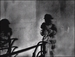 A supervisor monitoring a training burn can watch firefighters standing and walking because he is equipped with a TI. The white cloud surrounding the firefighters is superheated gases, indicating that the firefighters are ignoring basic safety as well as warning signs.