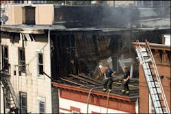 Firefighters stand on the roof of a damaged structure at the scene of an early morning apartment fire, in Union City, N.J., Saturday, Sept. 9, 2006. One firefighter was killed and four injured.
