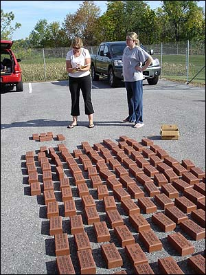 NFFF staff members, Judi Whitlow, left, and Rebecca Becker, left their desk jobs Tuesday to unpack and categorize engraved bricks before they are placed in the walk of honor.