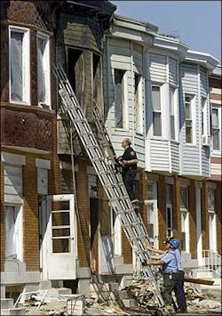 Investigators examine a fire damaged a row home in the Greektown neighborhood of Baltimore, Oct. 10.