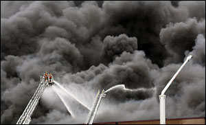 An aerial platform from Inver Grove Heights is dwarfed by the heavy smoke.
