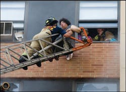 Firefighters rescue occupants by aerial ladder.