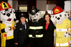 Upton, MA, Firefighter Bonnie Lopez and Marcia Gay Harden pose with fire prevention characters at the FDNY Fire Museum, where the celebration was held.