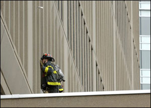 A firefighter looks into the window of a 17-story office building owned by the Massachusetts Institute of Technology, that was evacuated after smoke filled stairways and set off alarms Friday, Dec. 8, 2006, in Cambridge, Mass.