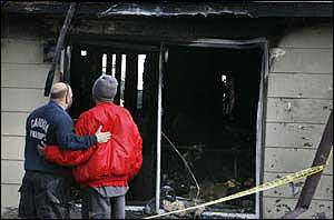 Cahokia Fire Department training officer Cris Burch comforts the boyfriend of the mother who perished in the house fire.