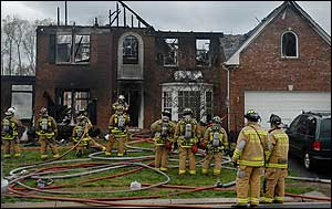 Firefighters gather in front of the house in which Firefighter was killed while searching for residents.