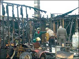 Dick Phillips, owner of of Vermont Field Sports, center, examines the remains of his Middlebury sporting goods store.