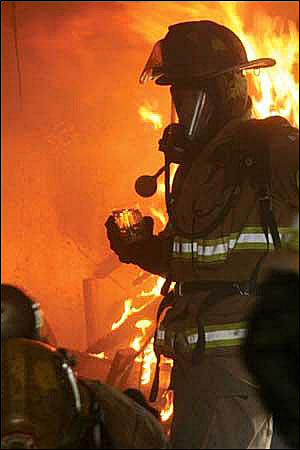 In this photo from Jan. 25, a firefighter is shown holding a glass of diesel fuel in a home purposely set on fire.