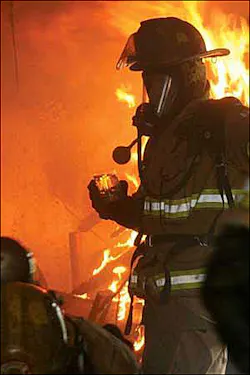 In this photo from Jan. 25, a firefighter is shown holding a glass of diesel fuel in a home purposely set on fire.