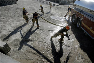 Firefighters carry a water hose near a tire fire in Las Vegas, Wednesday, June 20, 2007. Nearly 100 firefighters were dispatched to tackle the blaze that consumed a pile of tires stored in a lot west of the downtown casino corridor.