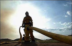 A Maui fire fighter fills up a temporary water tank used by helicopters while helping battle a wildfire in Olowalu, June 27.