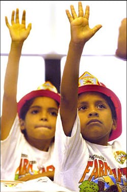 Children of migrant workers attend an annual safety camp in which the fire department has been a constant participant. The Spanish children develop an instant rapport and actively participate when the firefighters speak to them in Spanish.