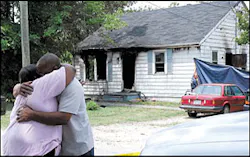 An unidentified man embraces Veronica Moore, the sister of one of the victims. An unidentified man embraces Veronica Moore, the sister of one of the victims.