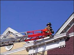 A firefighter from the station stands on the roof of a rowhouse where a small fire occured in the morning.