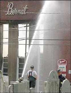 Hopedale firefighters spray down the front of the Bernat Mill complex during a fire at the mill, July 21. Hopedale firefighters spray down the front of the Bernat Mill complex during a fire at the mill, July 21.