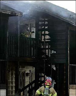 As one firefighter keeps watch, another walks along a second-floor balcony of the apartment complex. As one firefighter keeps watch, another walks along a second-floor balcony of the apartment complex.